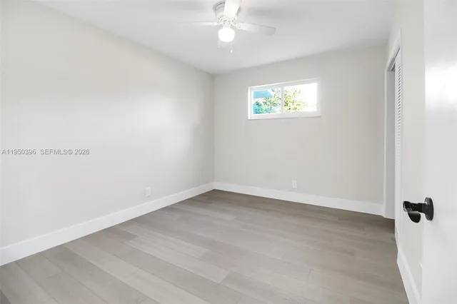 an empty room with a window and a fan