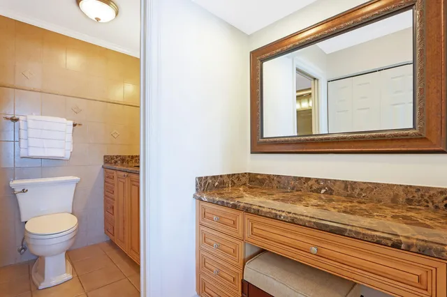 a bathroom with a granite countertop toilet sink and mirror