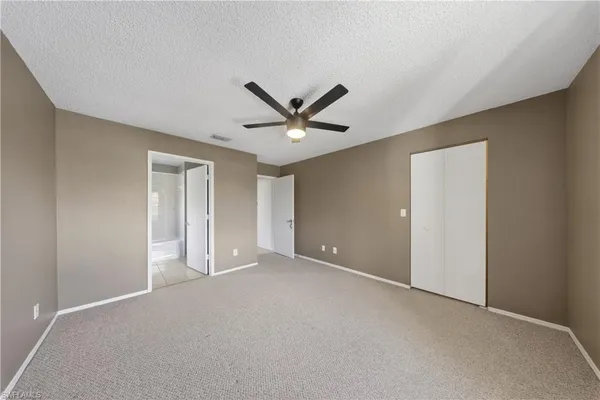 a view of an empty room with a ceiling fan and window