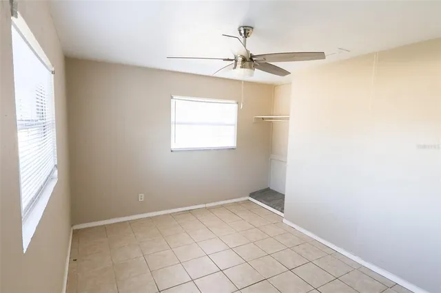 an empty room with windows and fan