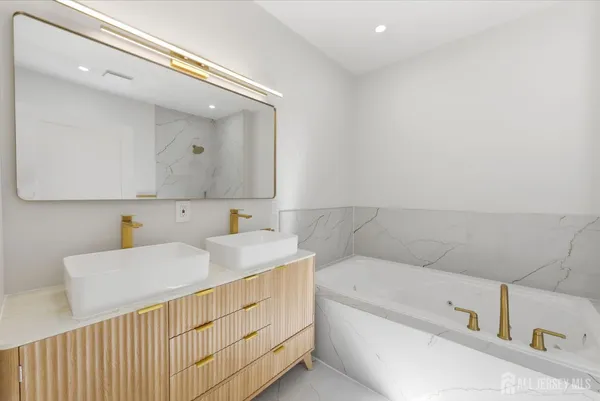 a bathroom with a double vanity sink mirror and bathtub