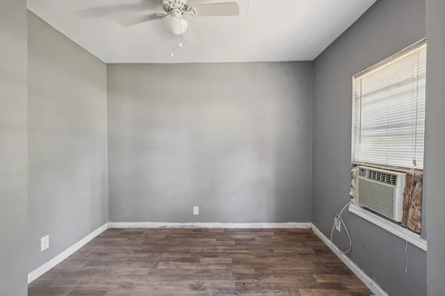a view of an empty room with a window and wooden floor
