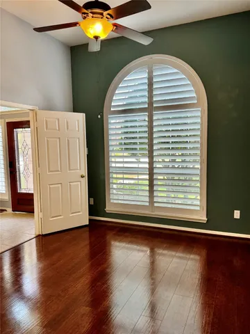 an empty room with wooden floor and windows