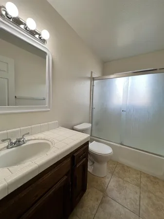 a bathroom with a granite countertop sink a toilet and a mirror