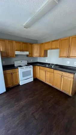 a kitchen with wooden floors and a view of living room