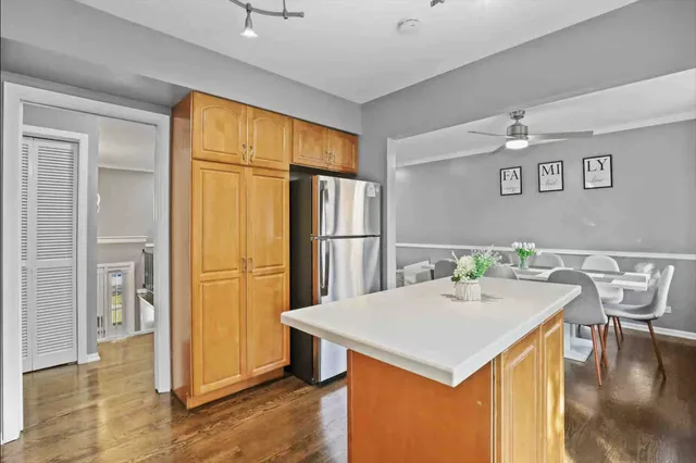 a kitchen that has a kitchen island wooden cabinets and refrigerator