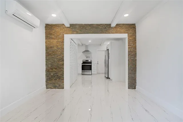 an empty room with kitchen view and windows