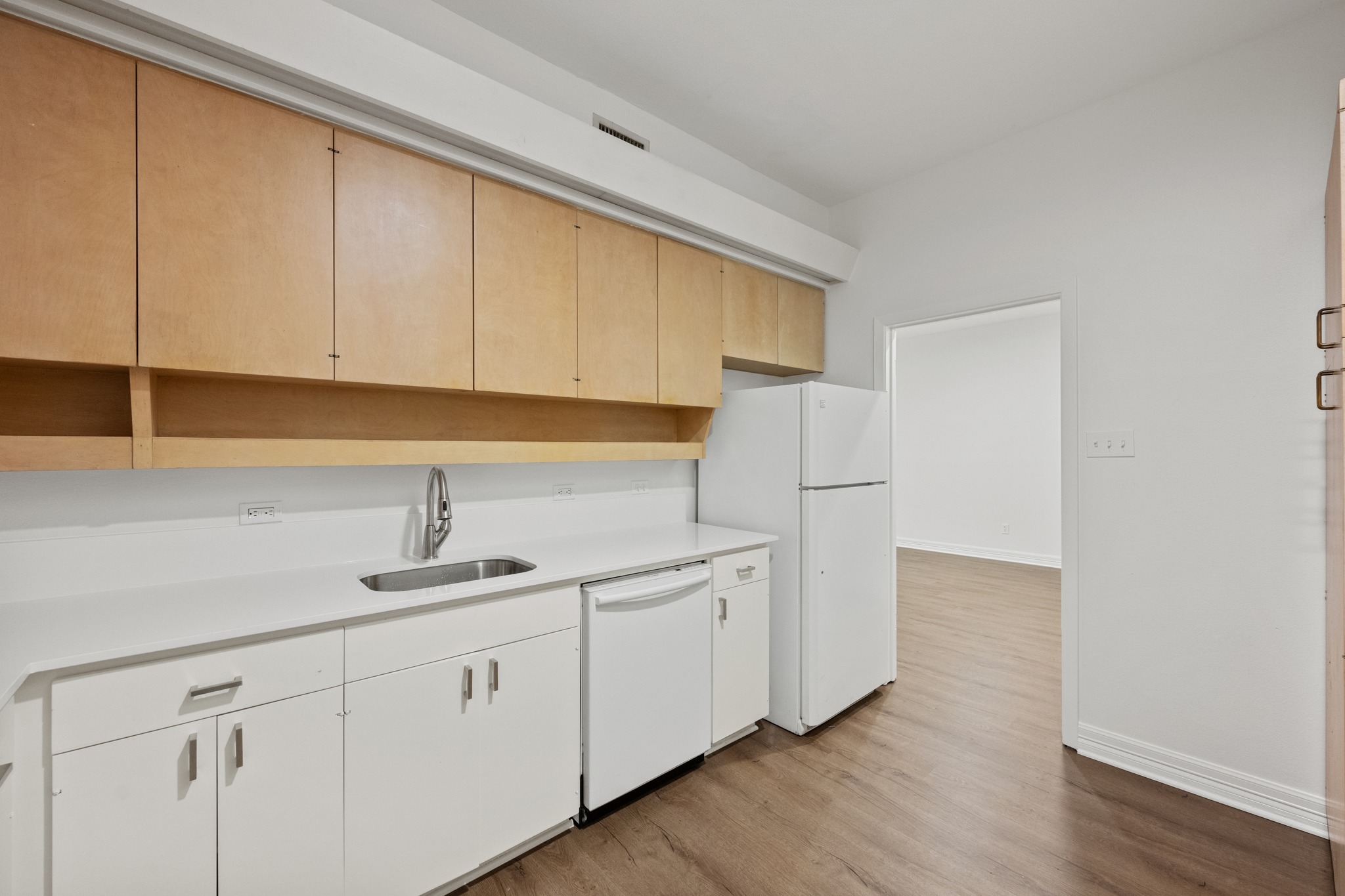 409 East 38th Street, Unit 101 Austin, TX 78705 - Photo 10 of 27 A streamlined kitchen showcasing light wood cabinetry and a functional layout. New counters, flooring and faucet.