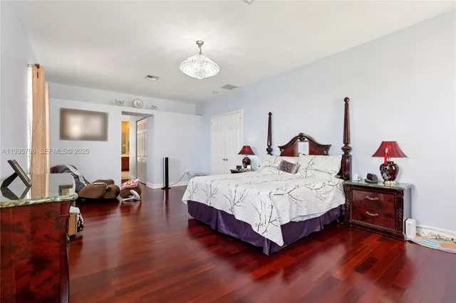 a spacious bedroom with a bed and wooden floor