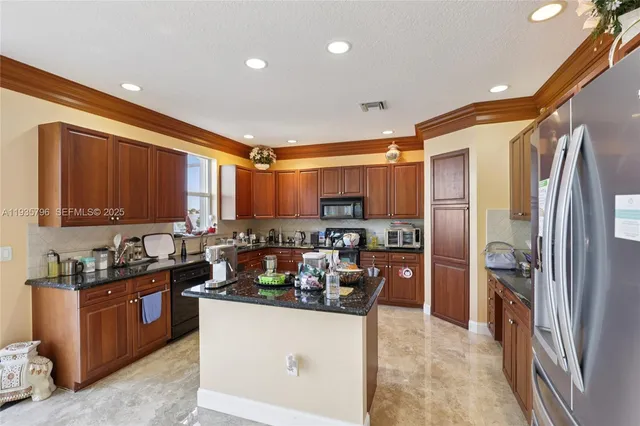 a kitchen with stainless steel appliances granite countertop a refrigerator a stove and a sink