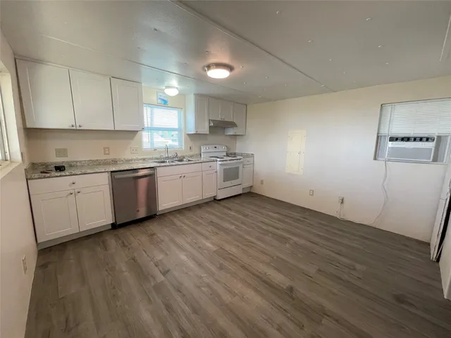 a kitchen with cabinets wooden floor and stainless steel appliances