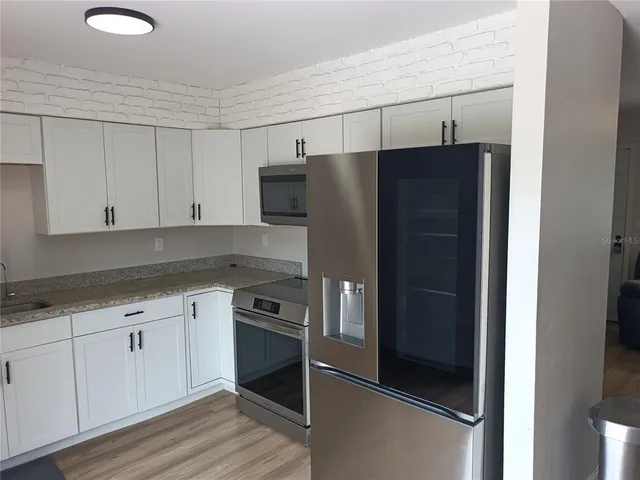 a kitchen with a refrigerator and white cabinets