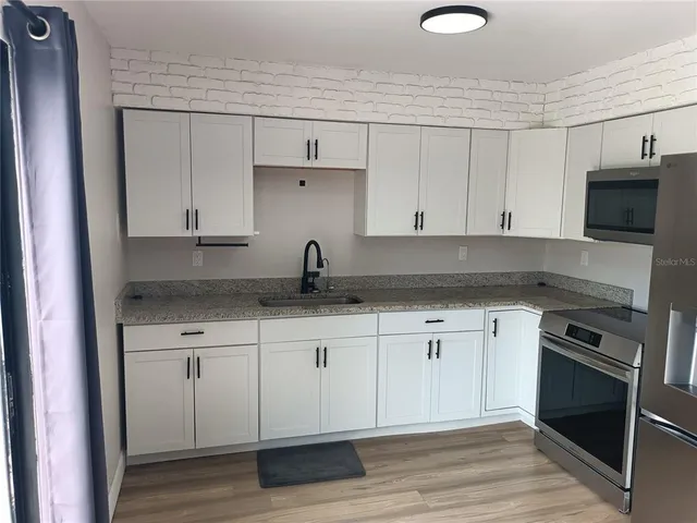 a kitchen with granite countertop white cabinets and stainless steel appliances