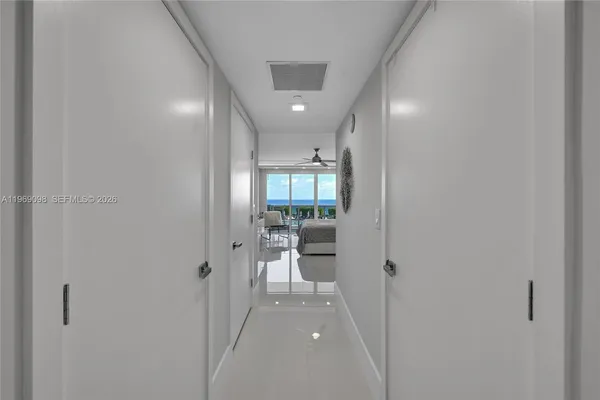a view of a hallway with wooden floor and a bathroom