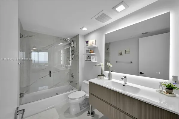 a bathroom with a double vanity sink toilet mirror and bathtub