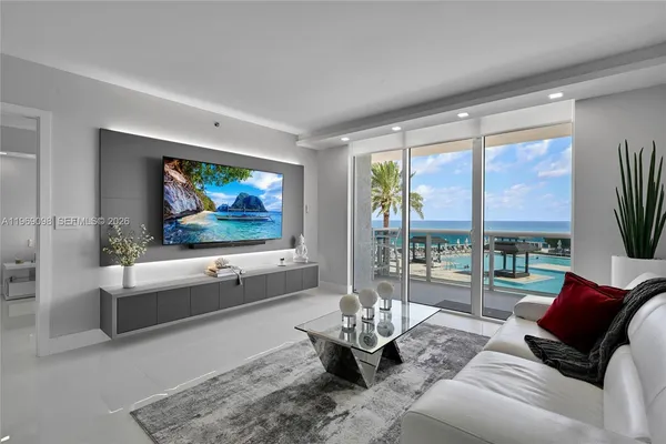 a living room with furniture floor to ceiling window and a flat screen tv