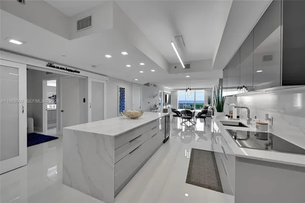 a large white kitchen with lots of counter space wooden floor and stainless steel appliances