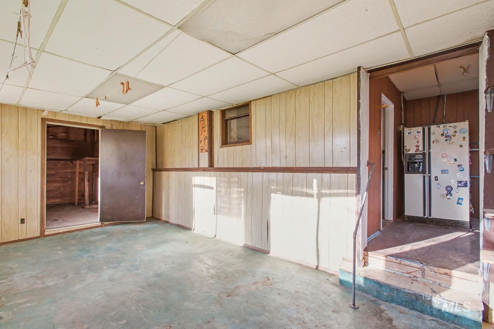 332 High Street Pomeroy, WA 99347 - Photo 16 of 23 Below grade area featuring a paneled ceiling, wooden walls, and white refrigerator with ice dispenser