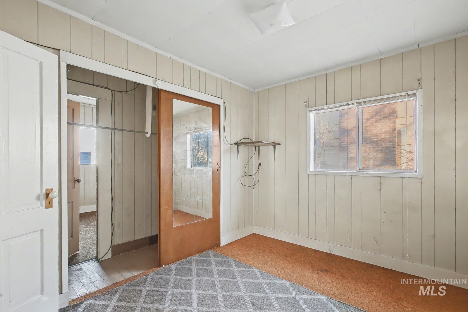 332 High Street Pomeroy, WA 99347 - Photo 9 of 23 Unfurnished bedroom with multiple windows, wood walls, and carpet floors