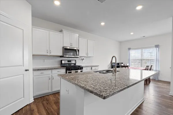 a kitchen with kitchen island granite countertop a stove sink and cabinets