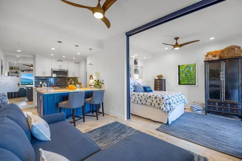 a living room with furniture kitchen view and a wooden floor