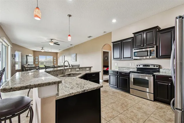 a kitchen with stainless steel appliances kitchen island granite countertop a refrigerator a stove a microwave oven a sink with island and chairs in it