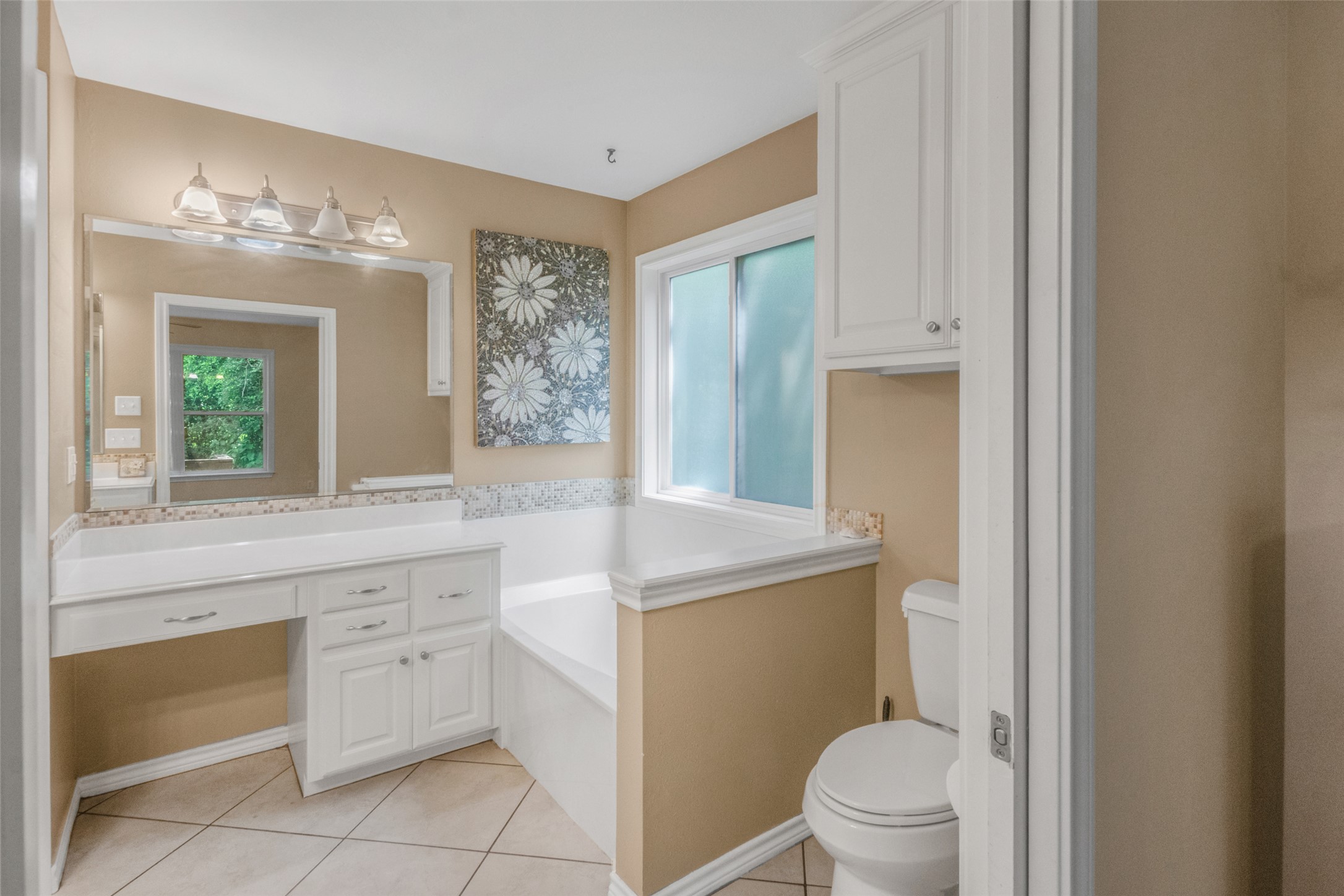 9997 Calhoun Road Bryan, TX 77808 - Photo 19 of 28 White cabinetry paired with neutral tile flooring anchors this functional bathroom layout.