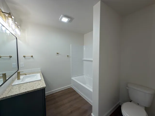 a bathroom with a granite countertop sink toilet and shower