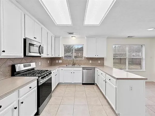 a kitchen with cabinets appliances a sink and a window