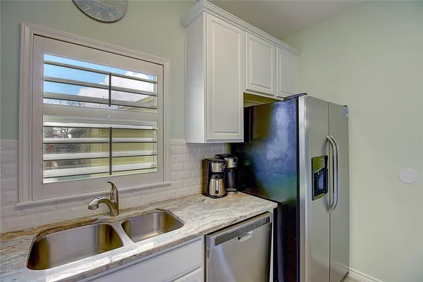 a kitchen with stainless steel appliances granite countertop a sink a refrigerator and a window