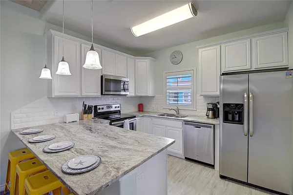 a kitchen with stainless steel appliances granite countertop a sink a stove a microwave a refrigerator a counter space and cabinets
