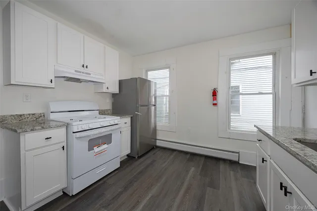 a hallway with granite countertop white cabinets and wooden floor