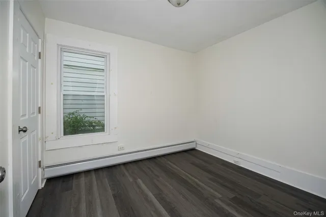a view of an empty room with wooden floor and window
