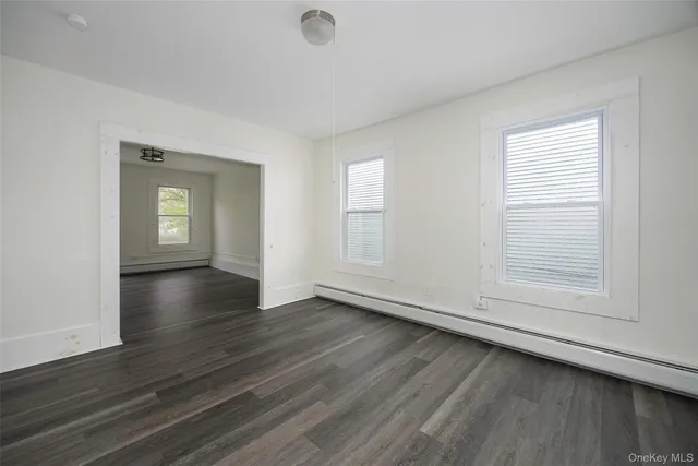 a view of an empty room with a window and wooden floor