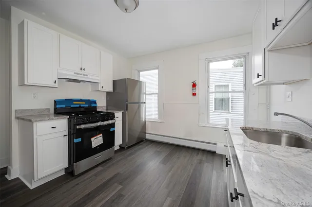 a kitchen with granite countertop white cabinets sink and a window