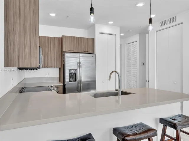 a kitchen with kitchen island granite countertop a sink stainless steel appliances and cabinets