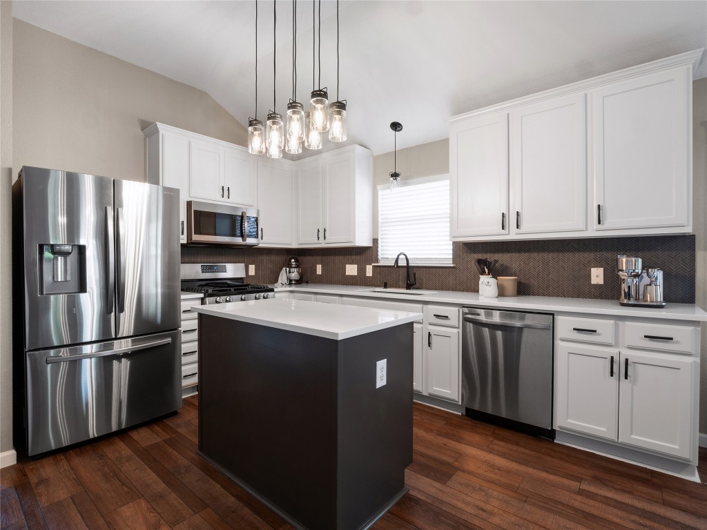 a kitchen with stainless steel appliances granite countertop a refrigerator a sink dishwasher a stove and white cabinets with wooden floor