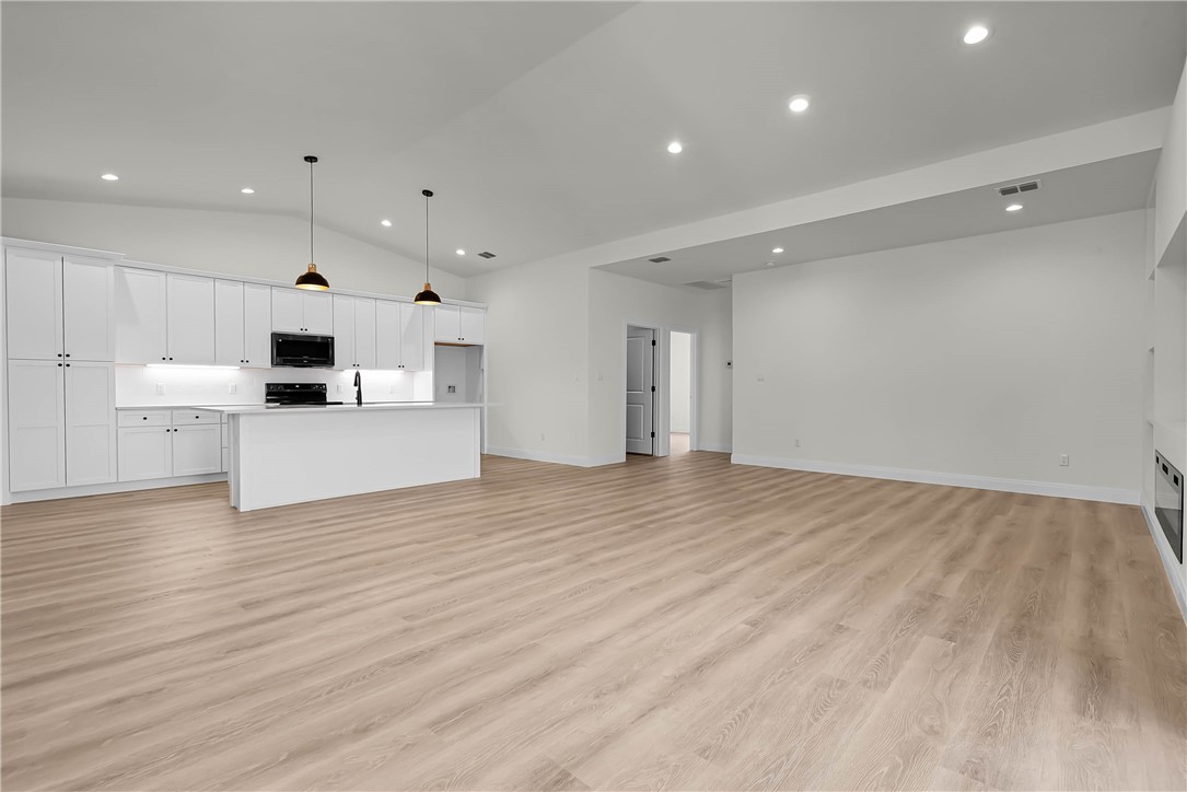 a view of a kitchen with kitchen island a sink wooden floor and a refrigerator