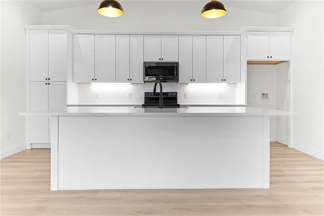 a kitchen with kitchen island white cabinets and stainless steel appliances