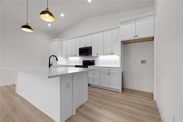 a kitchen with cabinets stainless steel appliances and wooden floor