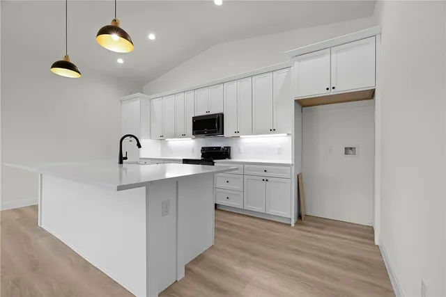 a kitchen with cabinets stainless steel appliances and wooden floor