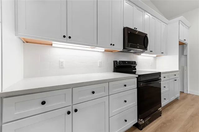 a kitchen with white cabinets and black appliances