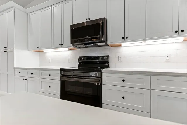 a kitchen with white cabinets and black appliances