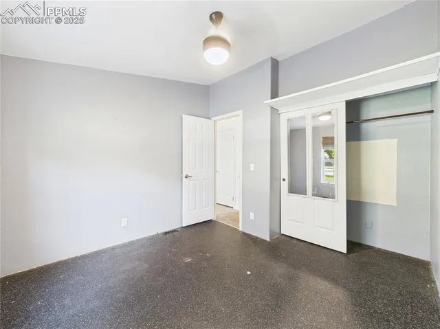 an empty room with windows and fan