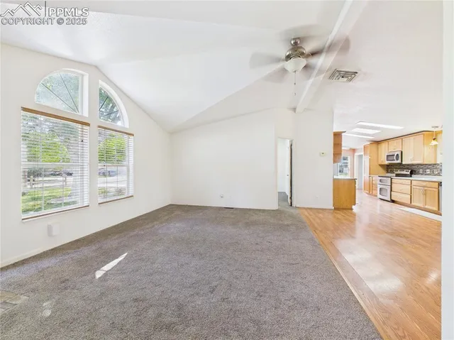 a view of an empty room with chandelier fan and a window
