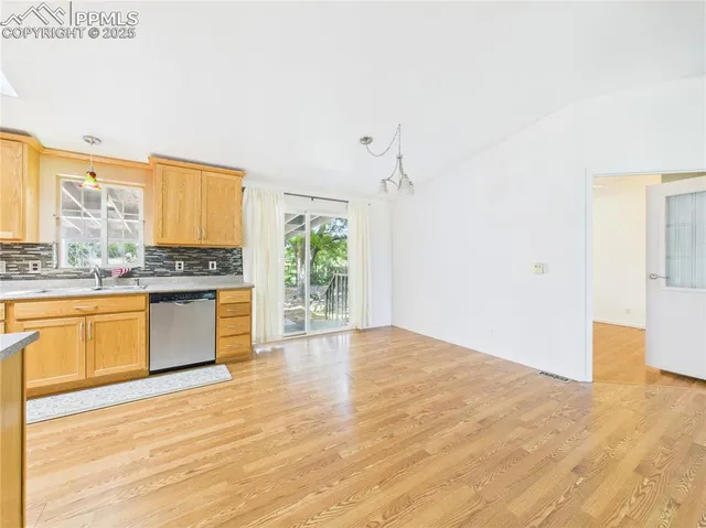 a view of a kitchen with kitchen island a counter top space wooden floor and stainless steel appliances