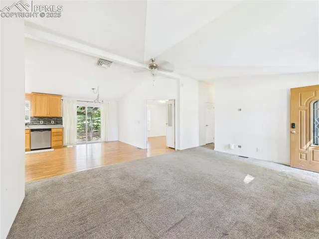 an empty room with windows and a kitchen view