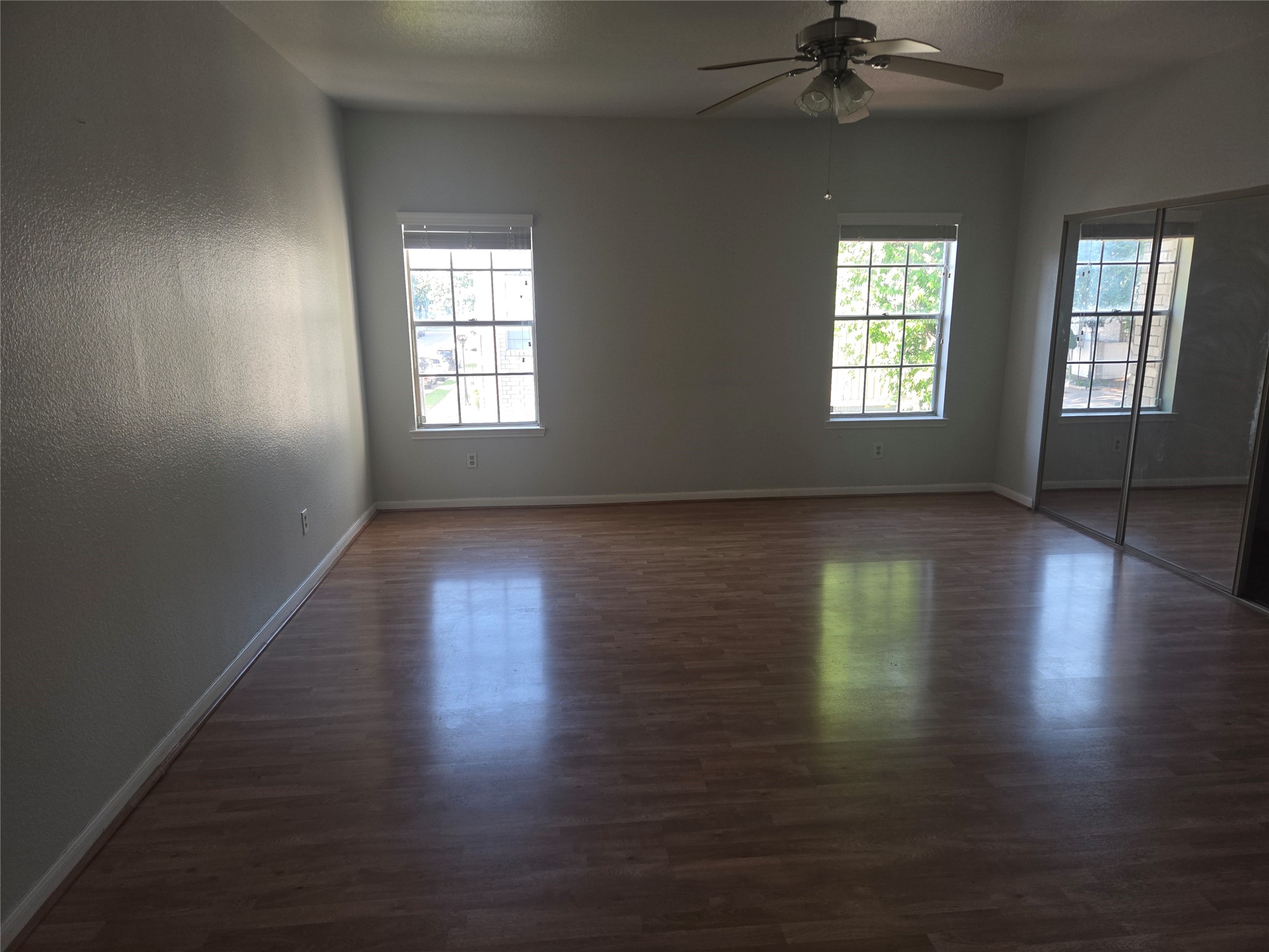 3780 Tanglewilde Street, Unit 501 Houston, TX 77063 - Photo 14 of 26 Spacious room with large windows for natural light, hardwood floors, ceiling fan, and mirrored closet doors.