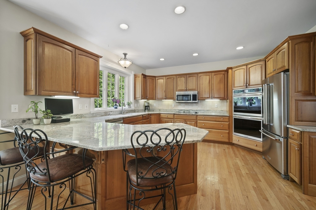 32 Bulkley Road Sudbury, MA 01776 - Photo 7 of 39 a kitchen with stainless steel appliances granite countertop a stove top oven a refrigerator a sink and a table with chairs