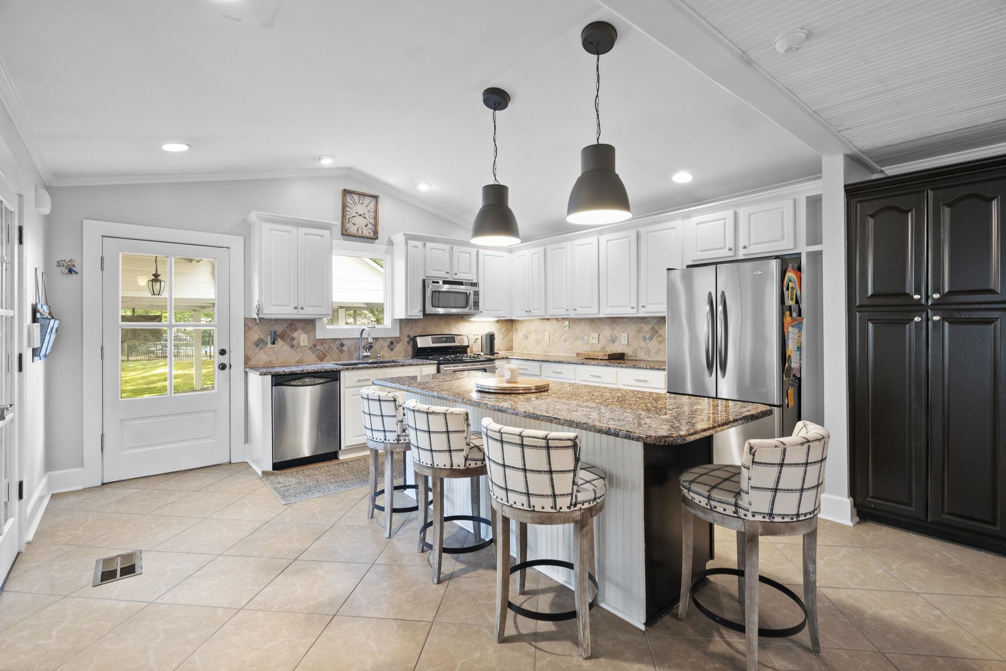 549 Peterson Lake Road Collierville, TN 38017 - Photo 9 of 34 a kitchen with stainless steel appliances kitchen island granite countertop a table chairs and a refrigerator
